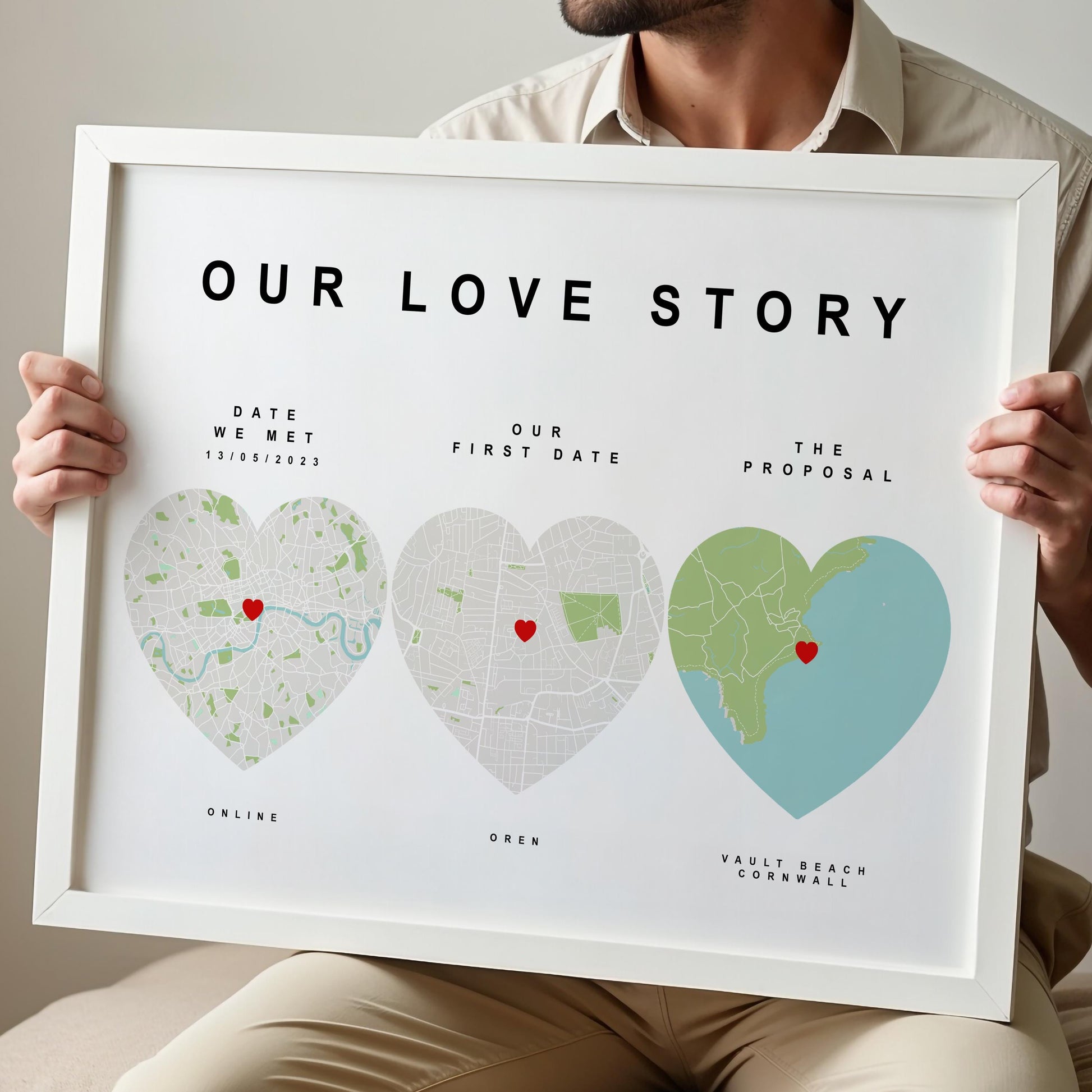 Person holding a framed map art titled 'Our Love Story' with heart-shaped maps of significant locations.