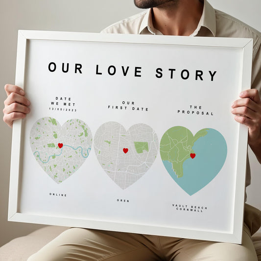 Person holding a framed map art titled 'Our Love Story' with heart-shaped maps of significant locations.